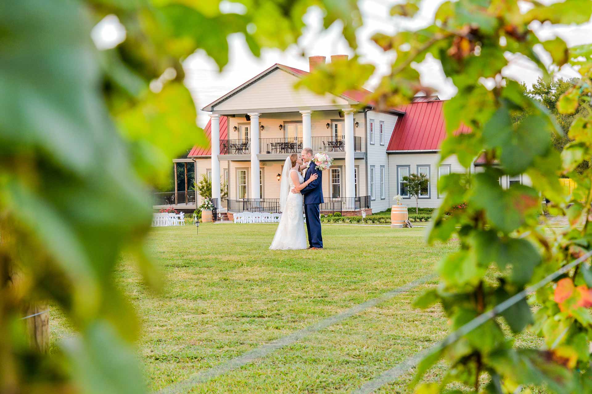 Bride and Groom Embracing in front of Rosemont through the vines